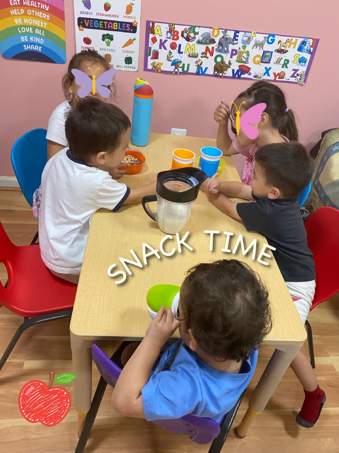 All of the 5 kids are sitting together at the table having their snacks!